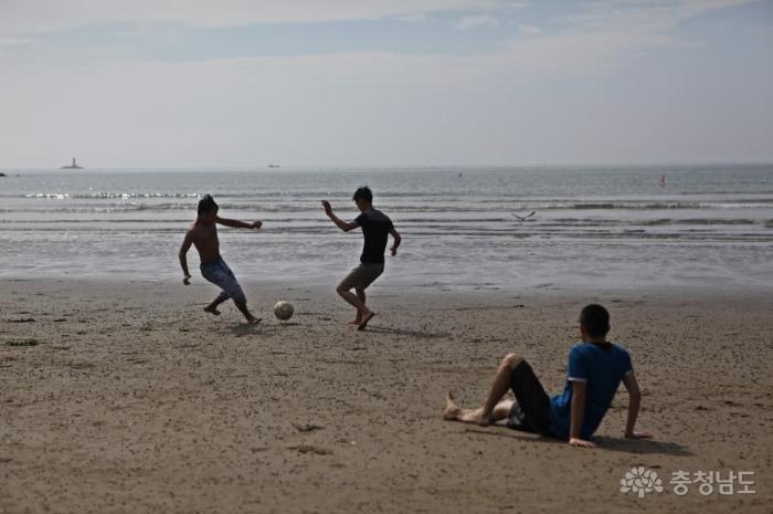 백사장에서 축구 경기를 하는 피서객들